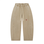 Pants: Villain Disruptor mineral-wash barrel-leg pants in tan with white drawstrings and red V logo.