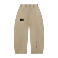 Villain unisex mineral-wash barrel-leg pants in tan with elastic waist, black hip patch, and red VILLAIN along the right leg.