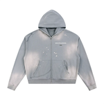Zippered hoodie in light sun-fade gray with frayed raw edges and white paint splatters; Wolvyn Apparel logo on chest.