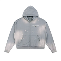 Zippered hoodie in light sun-fade gray with frayed raw edges and white paint splatters; Wolvyn Apparel logo on chest.