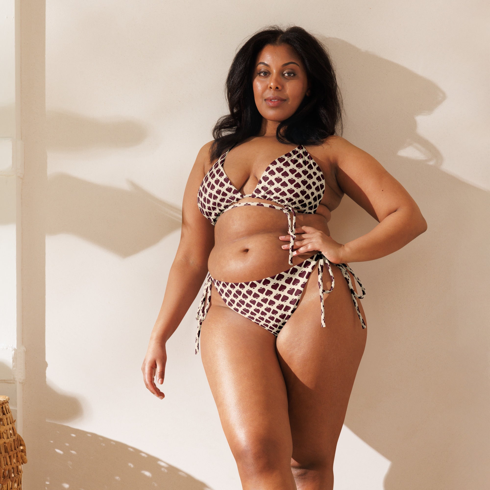 Woman modeling all-over print recycled string bikini with geometric pattern in natural light