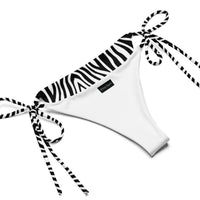 White string bikini bottom with zebra print trim and side ties on plain background
