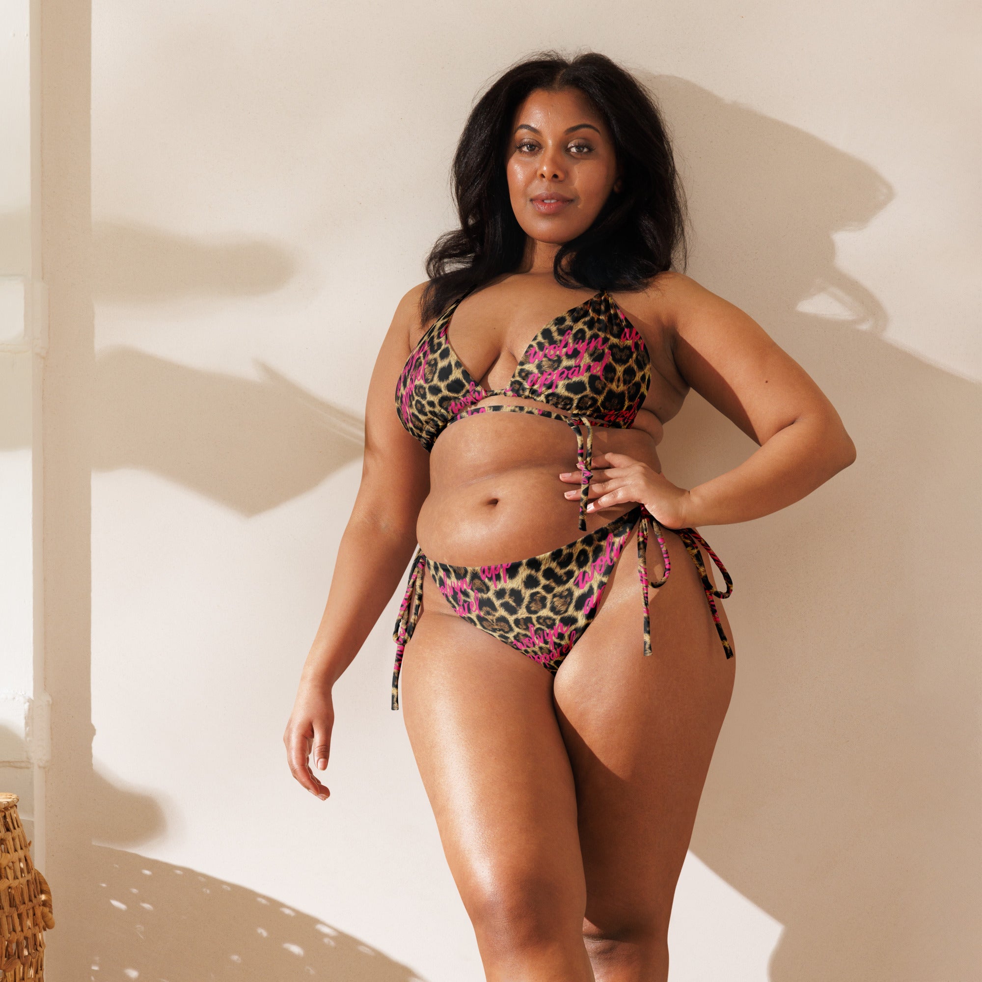 Woman modeling a leopard print string bikini with pink accents in natural indoor light