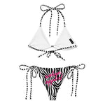 Black and white zebra print string bikini with pink script and striped ties, flat lay.