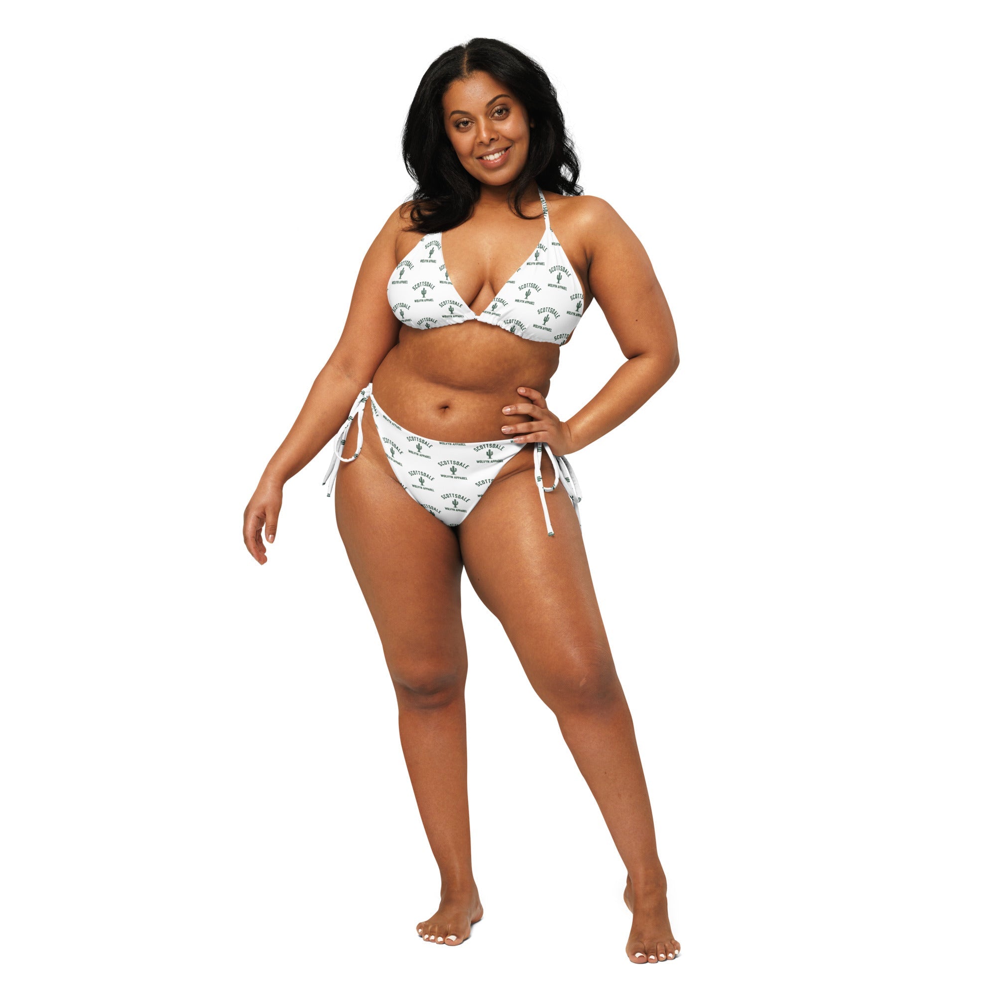 Woman modeling white recycled string bikini with all-over print design on plain background