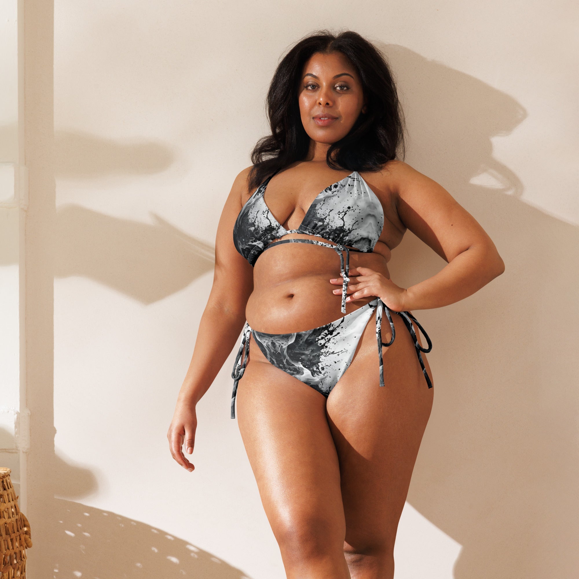 Woman modeling black and white marble print string bikini with side tie bottoms indoors