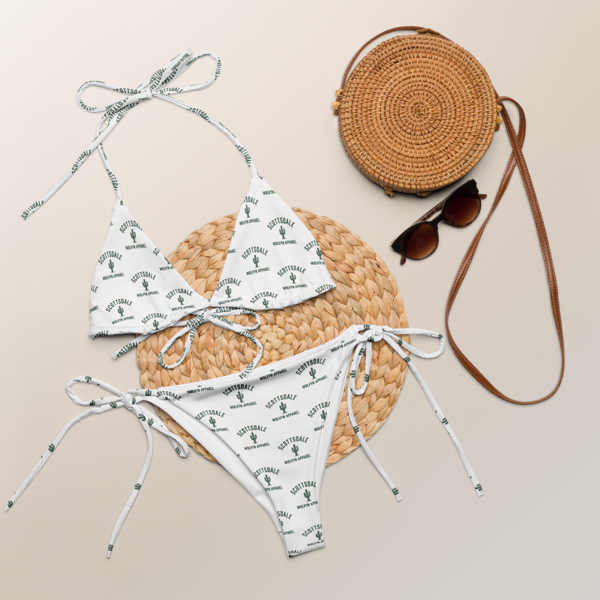 White string bikini set with Scottsdale cactus print, rattan bag, and sunglasses on beige
