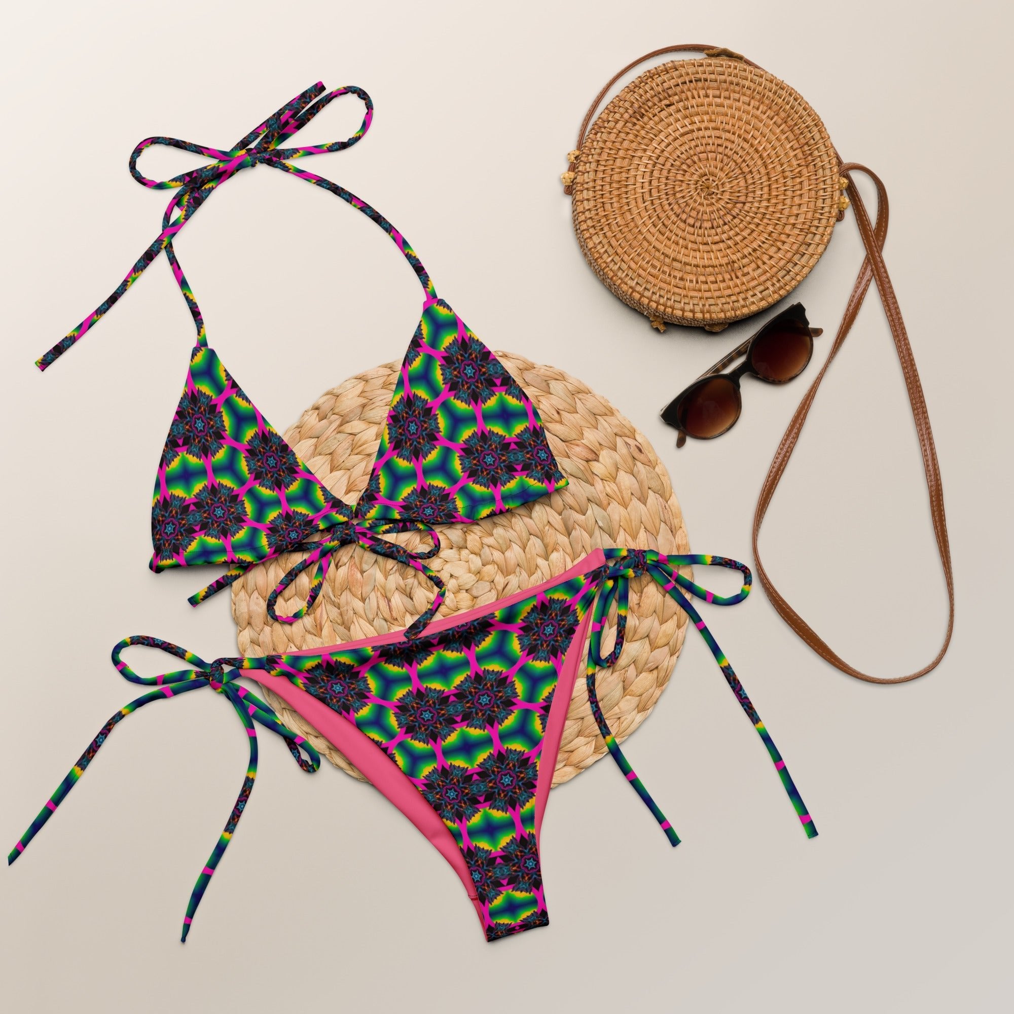 Colorful geometric print string bikini set with straw bag and sunglasses on neutral background