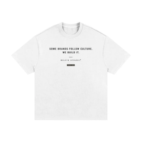 White cotton T-shirt flat lay with black slogan Some brands follow culture. We build it. Wolvyn Apparel.