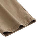 Close-up of tan cotton cargo pants hem with visible stitching, heavyweight streetwear fabric