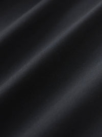 Close-up of smooth black dress pants fabric with soft diagonal folds