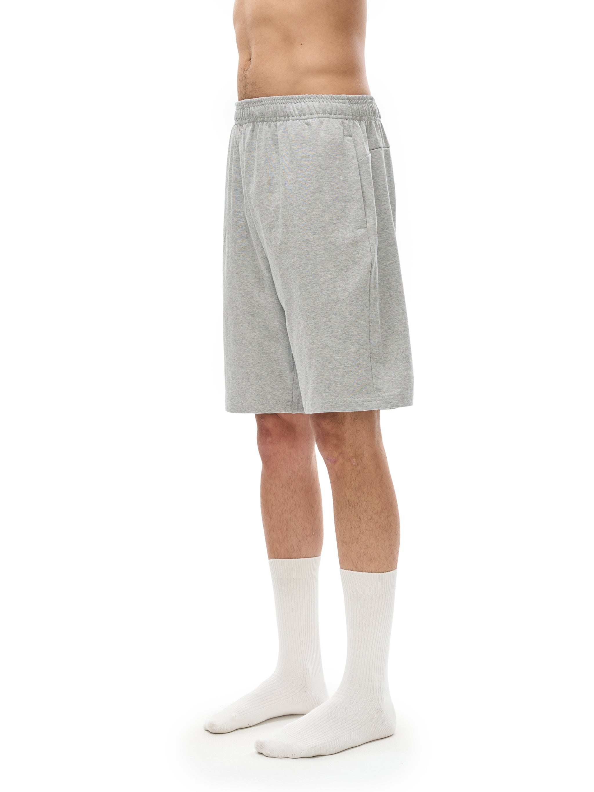 Side view of man wearing light grey heavyweight cotton shorts with elastic waistband