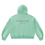 Wolvyn Apparel Foundations Layer 02 boxy fleece hoodie, mint green, unisex vintage-wash; back view shows FOUNDATIONS LAYER 02.