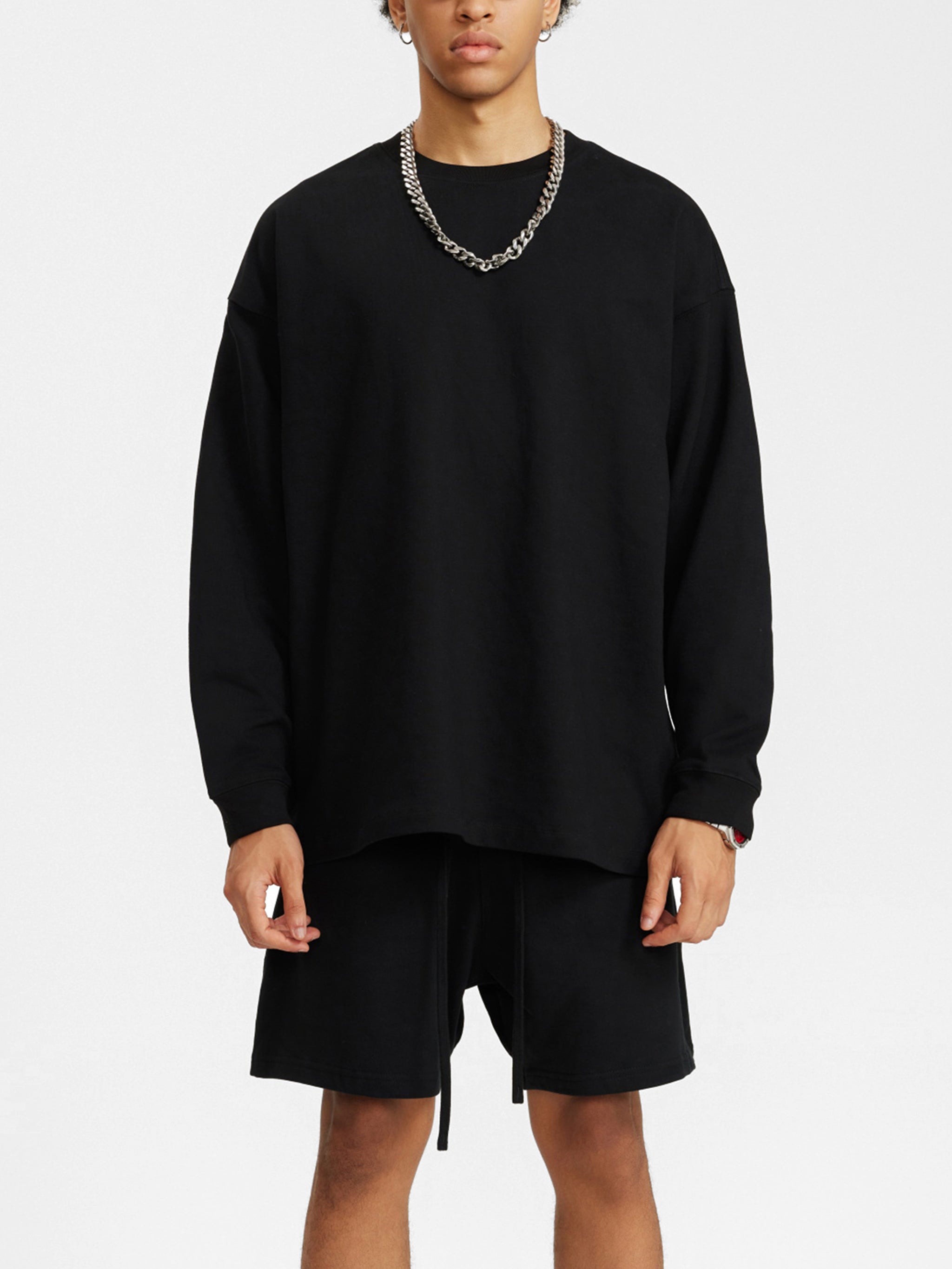 Man wearing black heavyweight oversized sweatshirt and matching shorts, minimal streetwear style