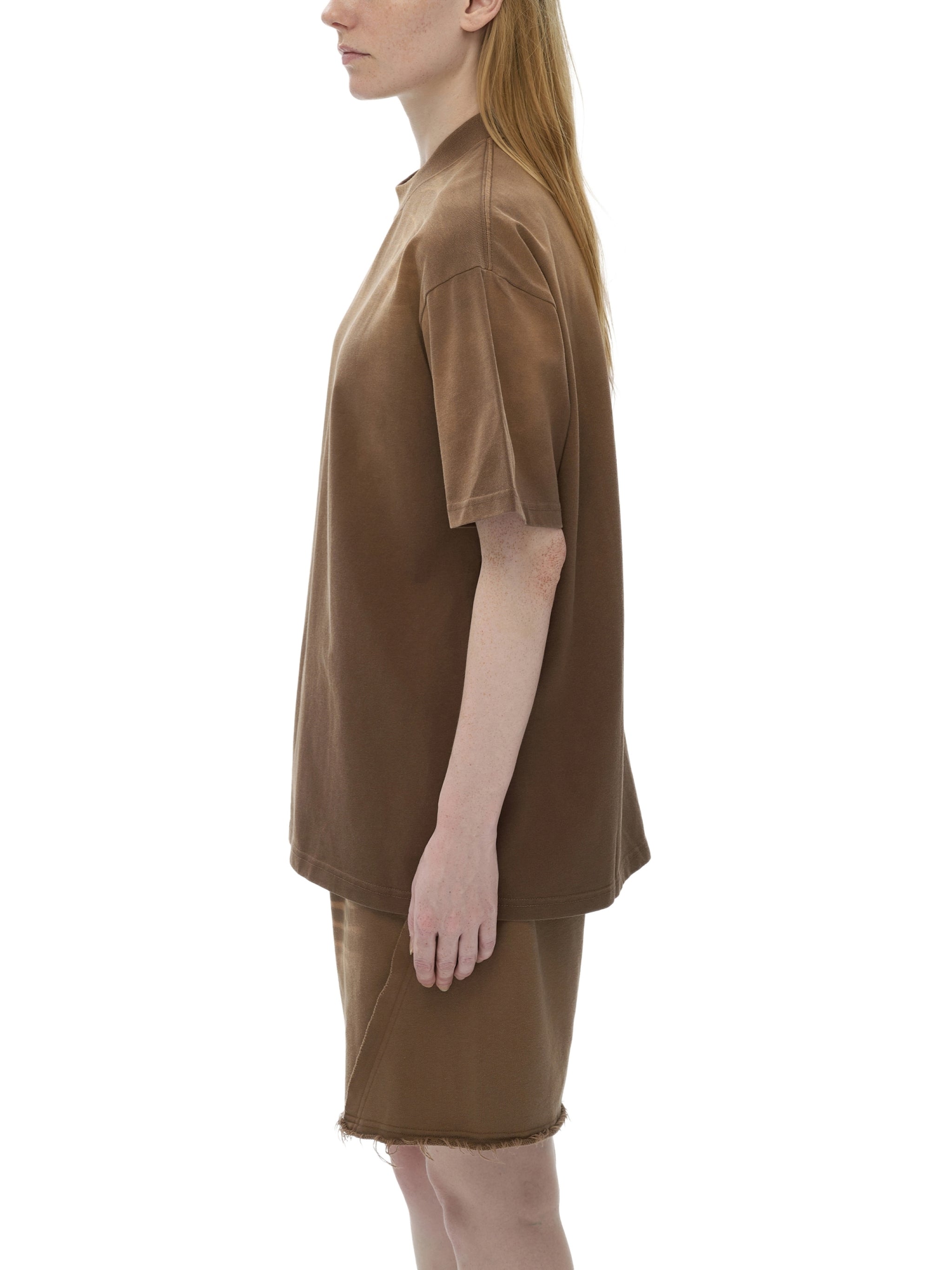 Side view of a woman in a brown oversized t-shirt and matching raw hem shorts