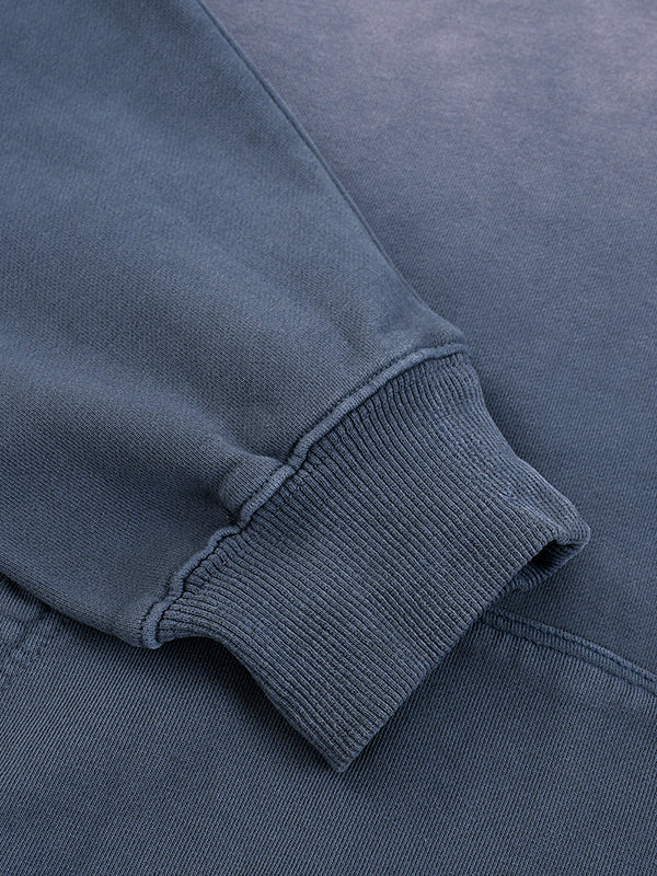 Close-up of a heavyweight dark blue sweatshirt sleeve with ribbed cuff and soft texture