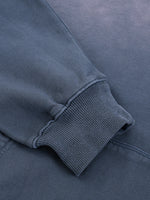 Close-up of a heavyweight dark blue sweatshirt sleeve with ribbed cuff and soft texture