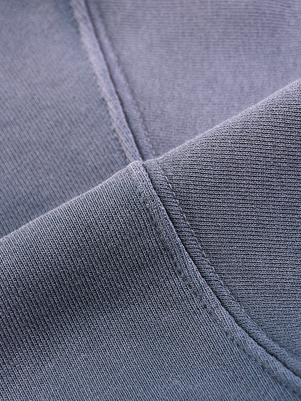 Close-up of heavyweight grey streetwear fabric showing thick stitching detail