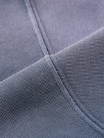 Close-up of heavyweight grey streetwear fabric showing thick stitching detail