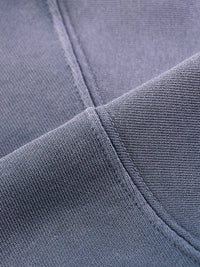 Close-up of heavyweight grey streetwear fabric showing thick stitching detail