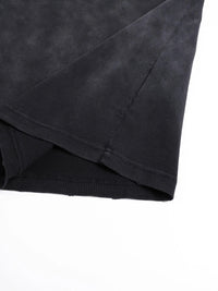 Tshirt close-up in black fabric with hand-frayed hem and sleeve seam.