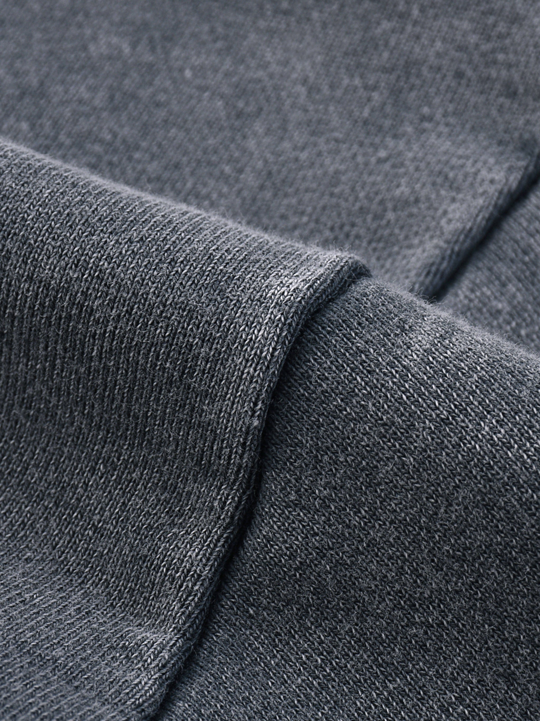 Close-up of heavyweight dark grey knit streetwear fabric with textured weave.