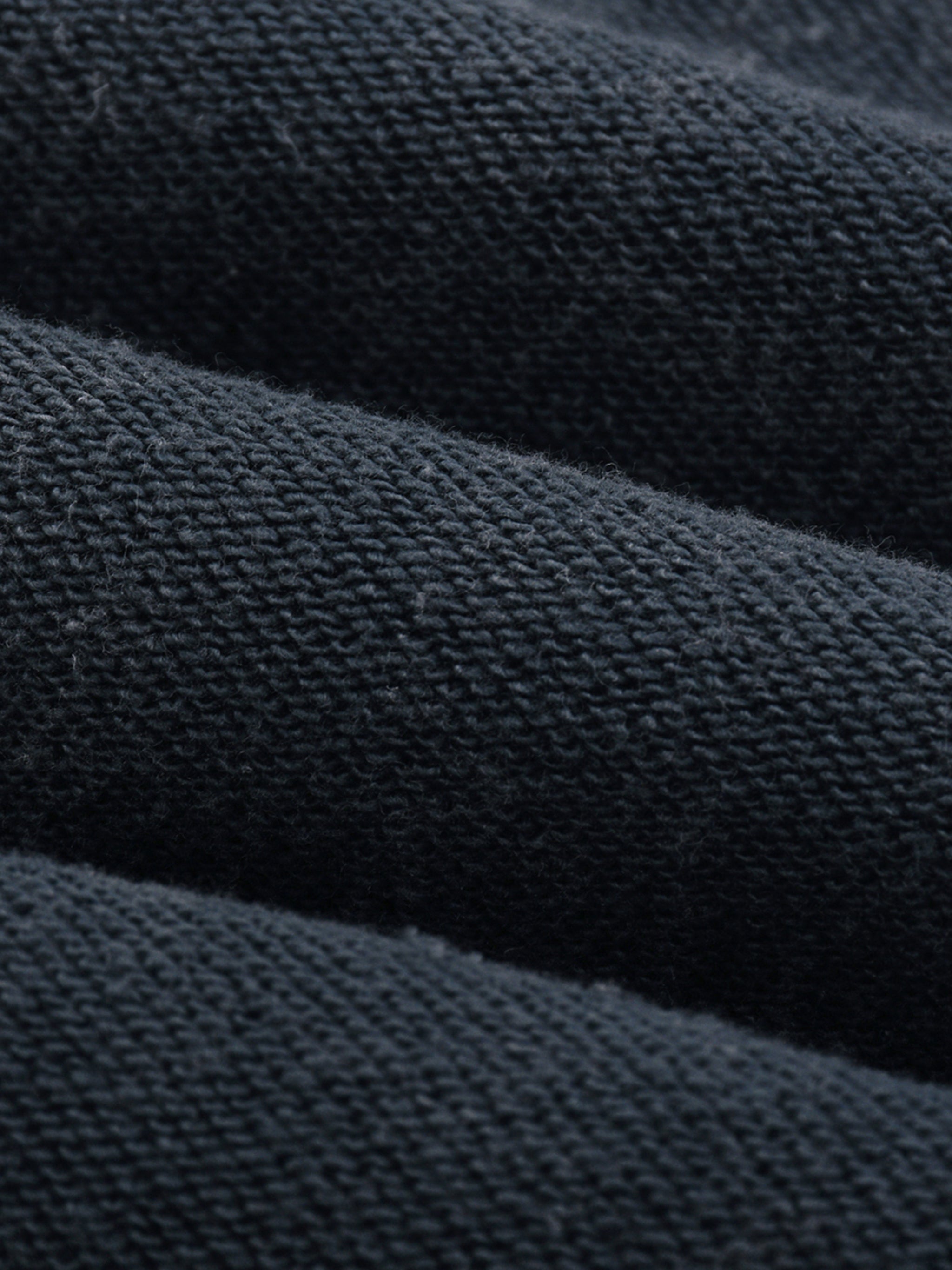 Close-up of heavyweight black knit fabric texture, premium streetwear textile detail
