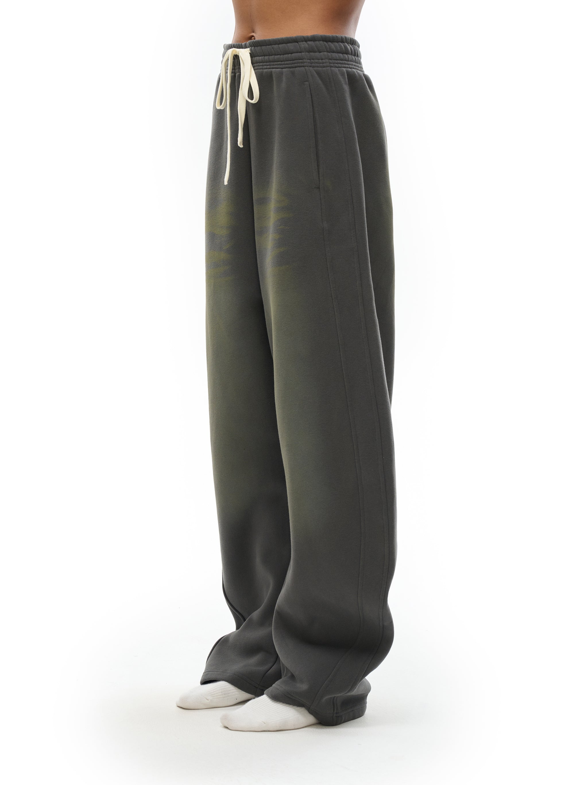 Wide-leg dark grey sweatpants with drawstring waist, streetwear style, worn by model.