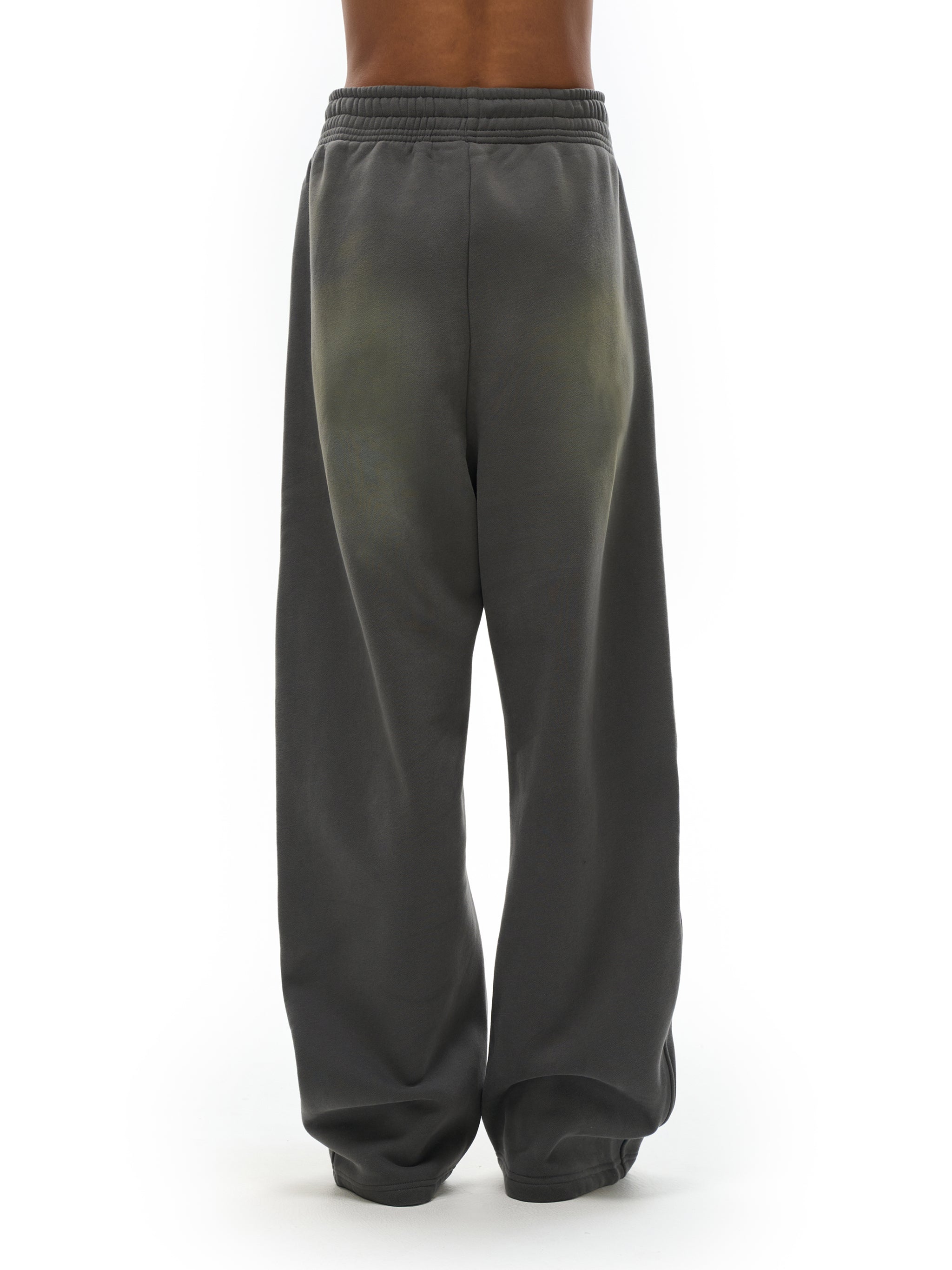 Back view of loose-fit charcoal sweatpants with elastic waistband, streetwear style