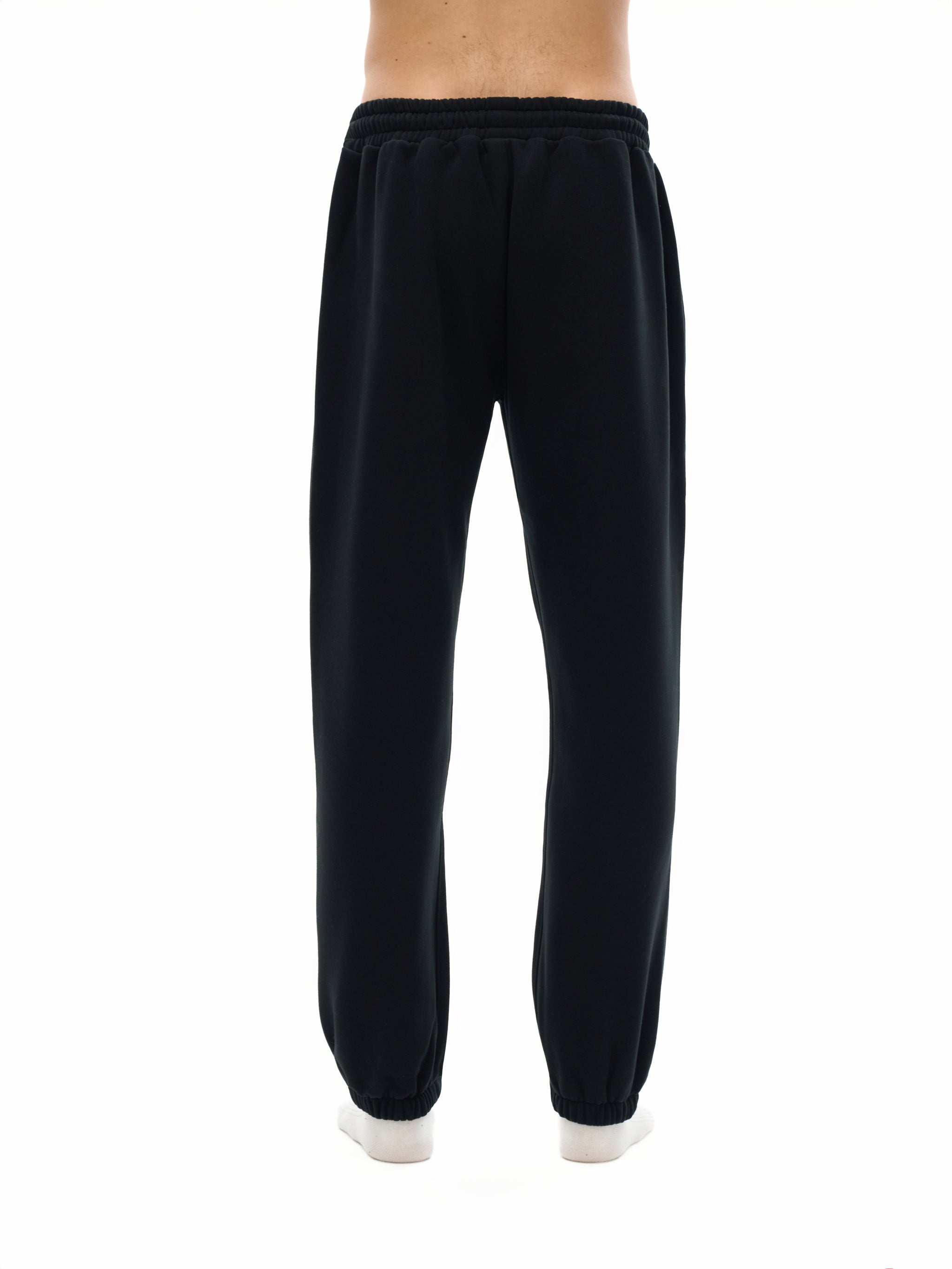 Back view of a person wearing black heavyweight streetwear sweatpants with elastic cuffs