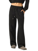 Woman wearing black wide-leg sweatpants with drawstring waist, relaxed streetwear style