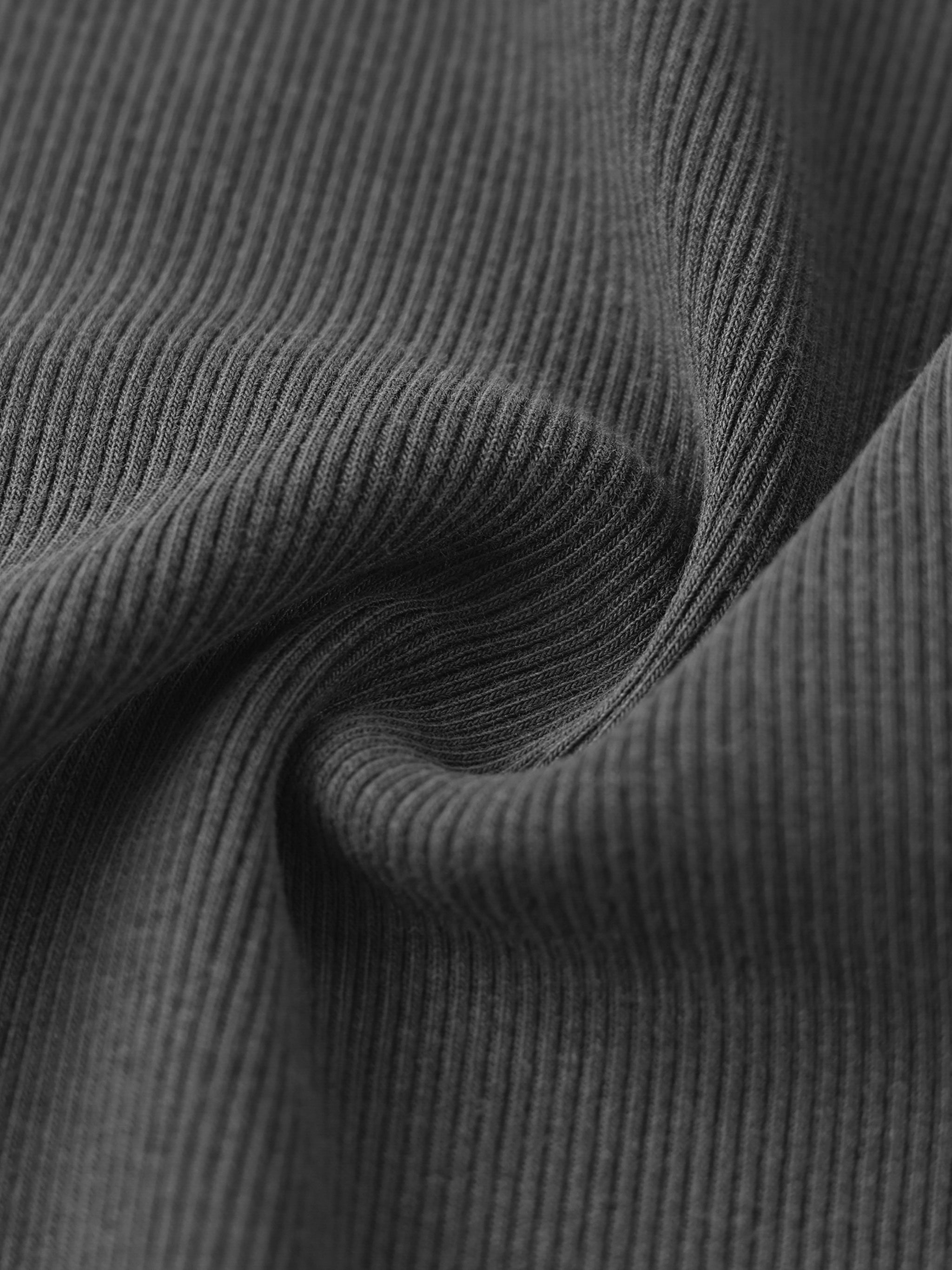 Close-up of heavyweight ribbed black fabric texture with soft folds.