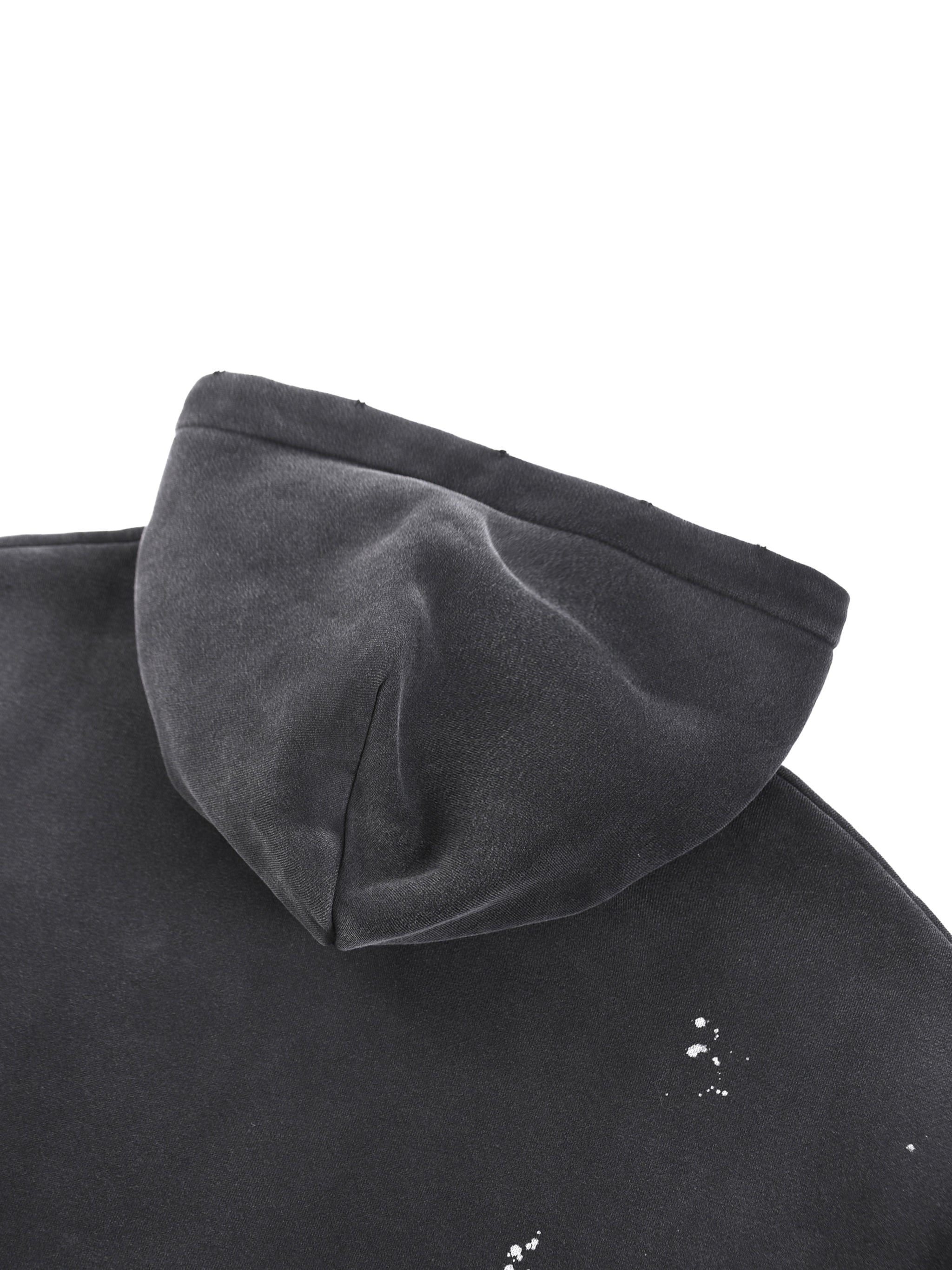 Close-up of black heavyweight hoodie hood with subtle paint splatter detail, streetwear style