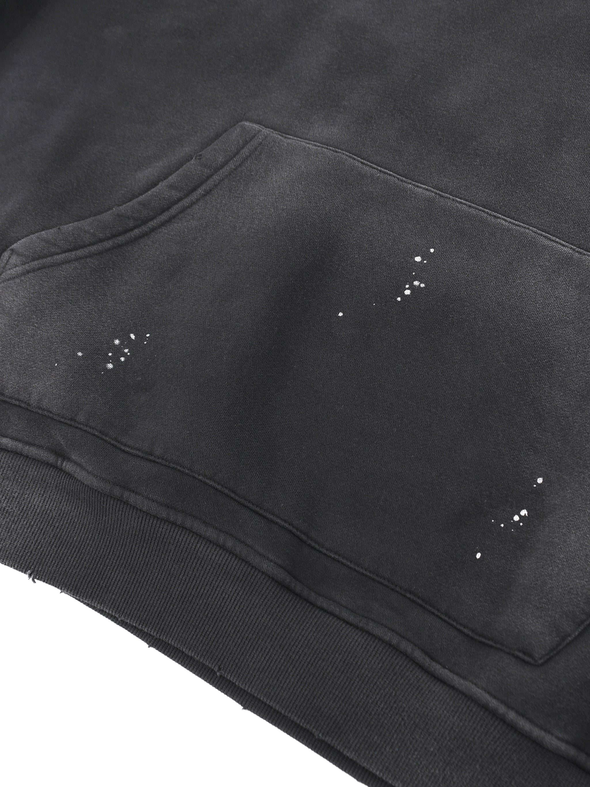 Close-up of black heavyweight streetwear hoodie with paint splatter details and kangaroo pocket