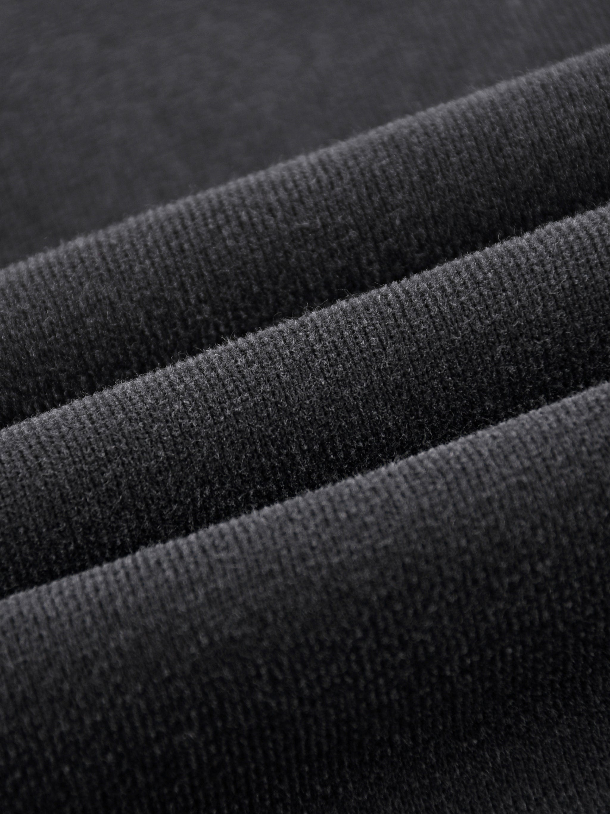 Close-up of heavyweight black streetwear fabric with soft, textured knit detail