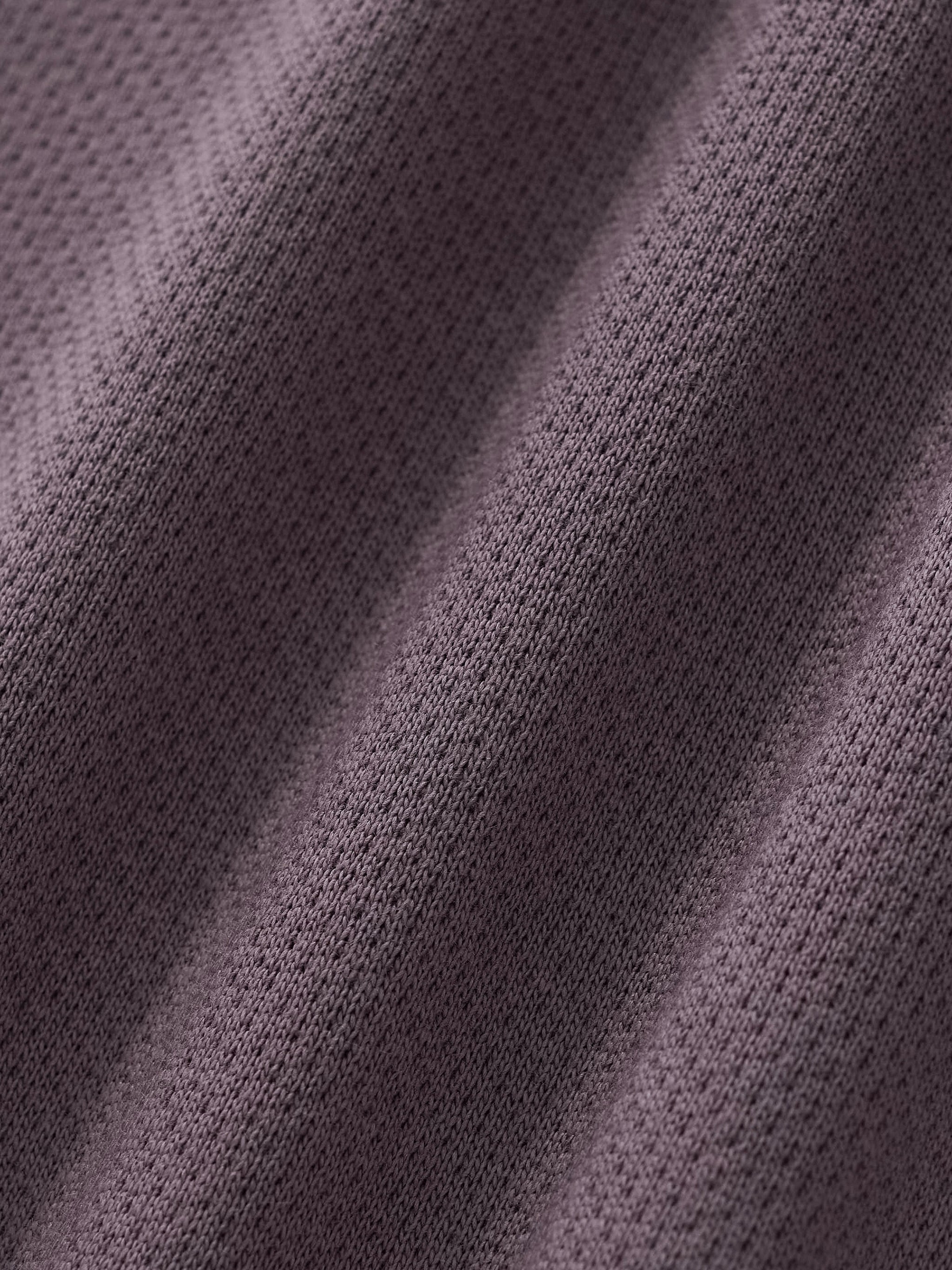 Close-up of heavyweight textured knit fabric in a soft gray color, streetwear material