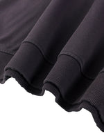Close-up of heavyweight black streetwear sweatshirt with ribbed cuffs and raw hem