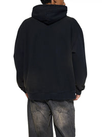 Back view of a person wearing a black heavyweight hoodie and washed denim jeans