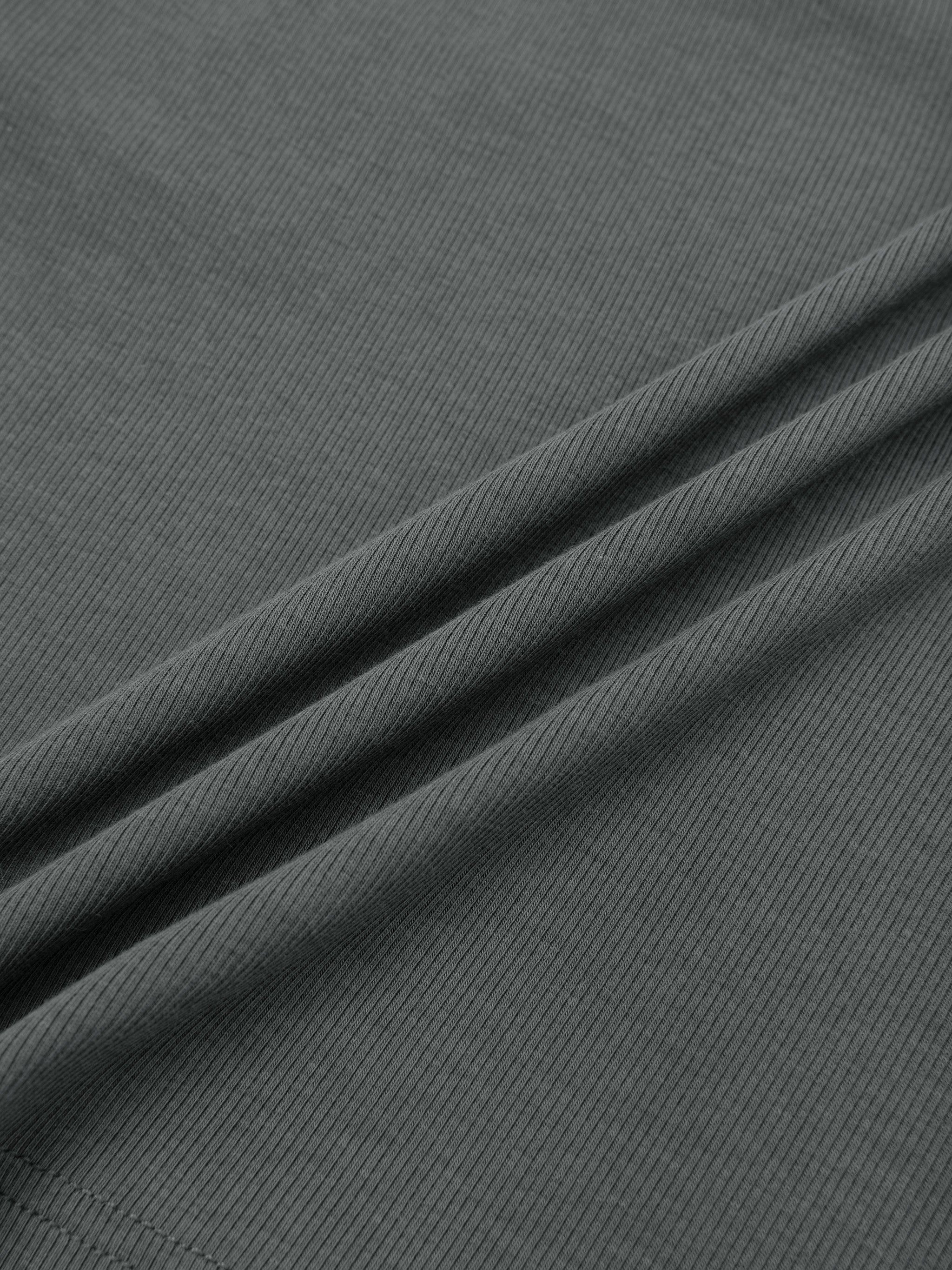 Close-up of heavyweight dark grey ribbed streetwear fabric with subtle texture