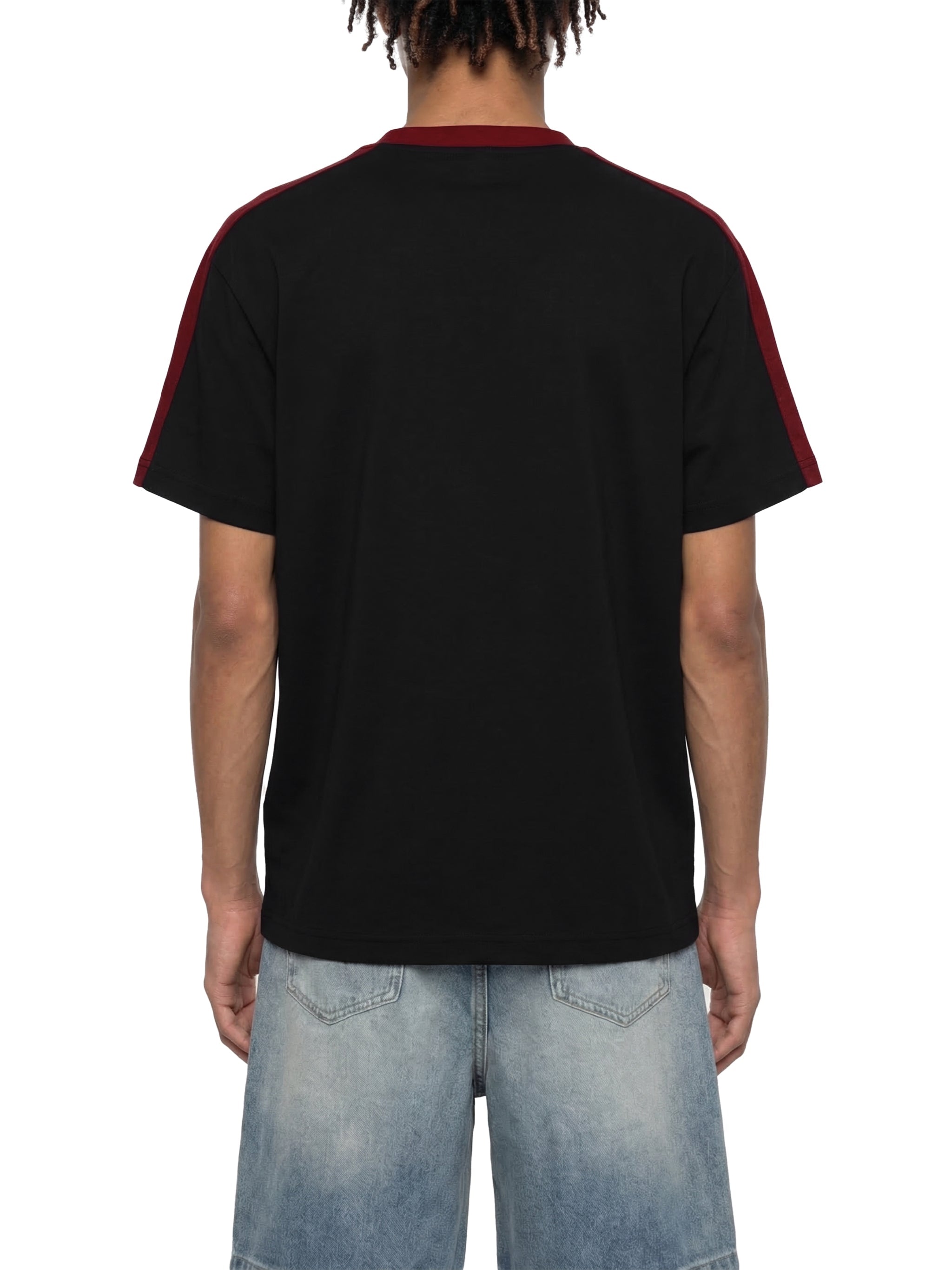 Back view of unisex black t-shirt with maroon stripes on shoulders, paired with denim shorts