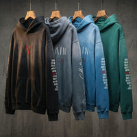 Four heavyweight sunfade oversized hoodies in black, grey, blue, and green on hangers