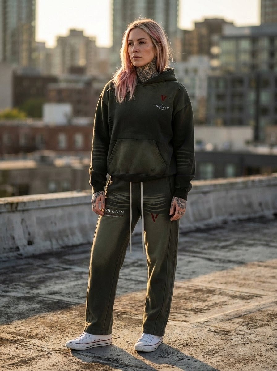 Woman wearing dark fleece hoodie and sweatpants set with V and VILLAIN logos, city rooftop background