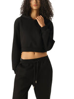 Woman wearing black cropped hoodie and matching sweatpants, minimalist streetwear style