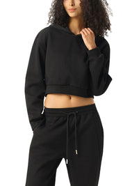 Woman modeling black cropped hoodie and sweatpants set against white background