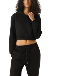 Woman wearing a black cropped hoodie and joggers, streetwear style, on white background