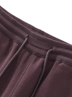 Close-up of brown heavyweight drawstring sweatpants with ribbed waistband and seam detail