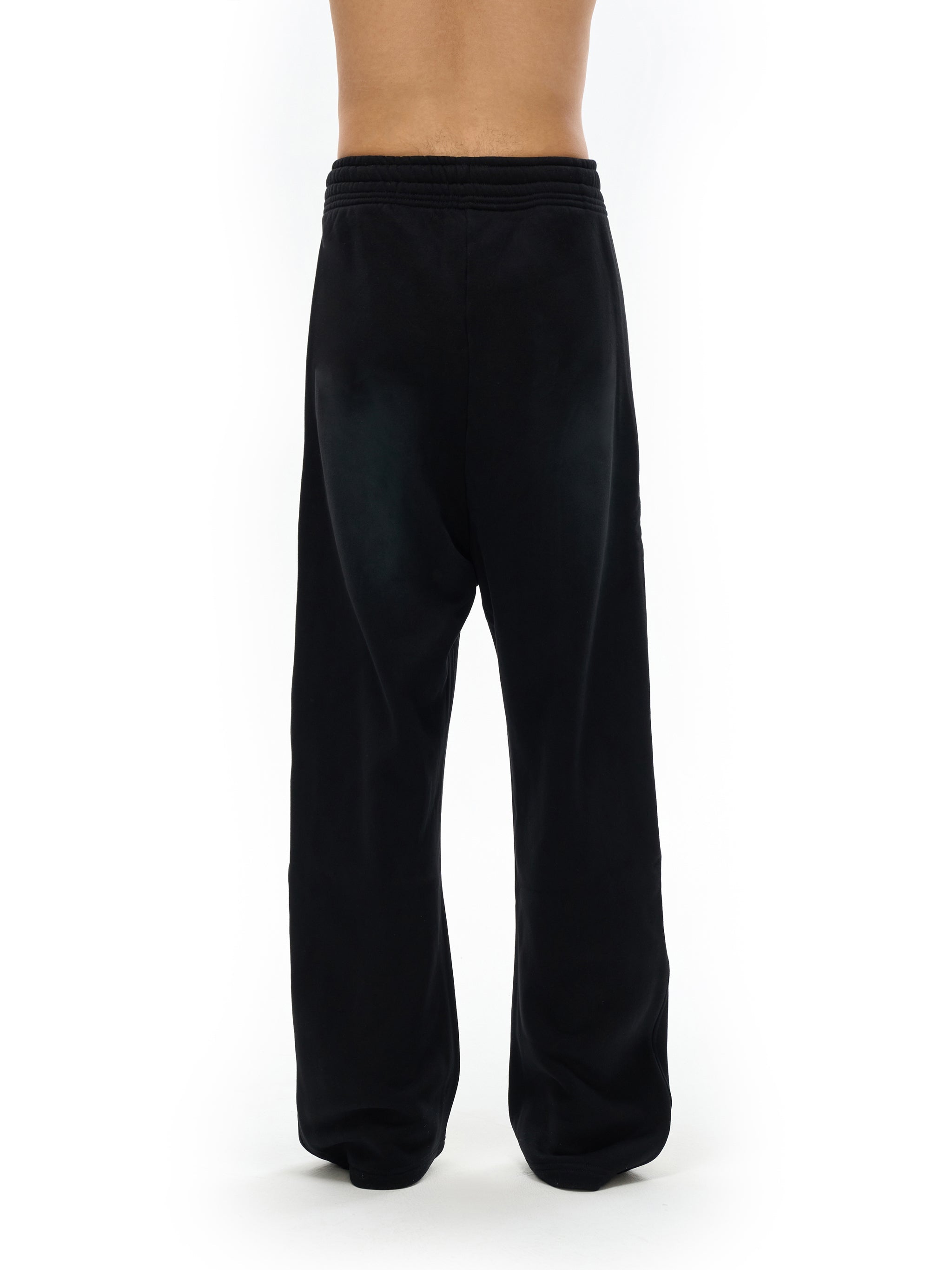 Back view of black fleece sweatpants with relaxed fit, elastic waistband, and straight leg design