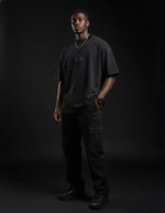 Man modeling black heavyweight knitted round neck t-shirt and cargo pants in studio.