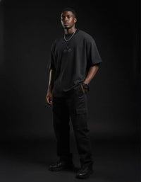 Man modeling black heavyweight knitted round neck t-shirt and cargo pants in studio.