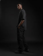Man wearing heavyweight black knitted round neck t-shirt and cargo pants in studio